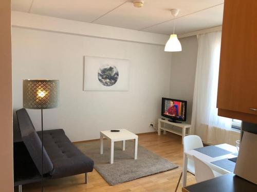 ein Wohnzimmer mit einem Sofa, einem Tisch und einem TV in der Unterkunft Kotimaailma - Kaksio saunalla Herttoniemessä in Helsinki