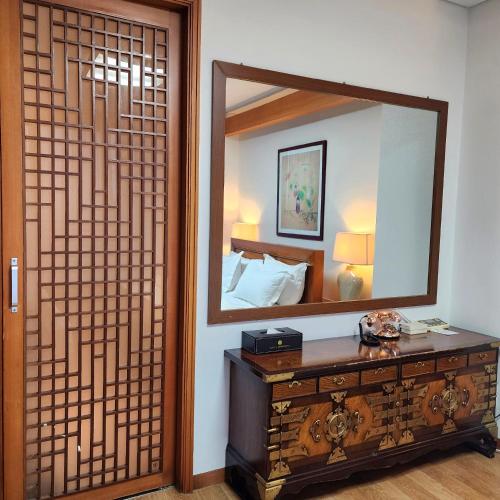 a bedroom with a mirror and a wooden dresser with a dresser at Hotel Maremons in Sokcho