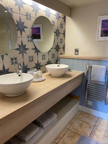 a bathroom with two sinks and a mirror at Blacksmith’s Barn - Cosy, Chilled & Dog Friendly. in Wykeham