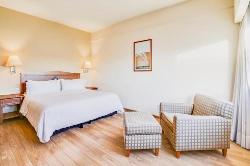 a hotel room with a bed and a chair at Fiesta Inn Torreon Galerias in Torreón