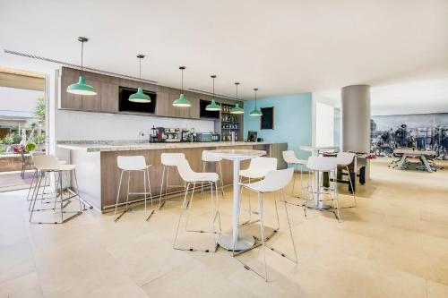 a kitchen with white stools and a counter top at Fiesta Inn Torreon Galerias in Torreón