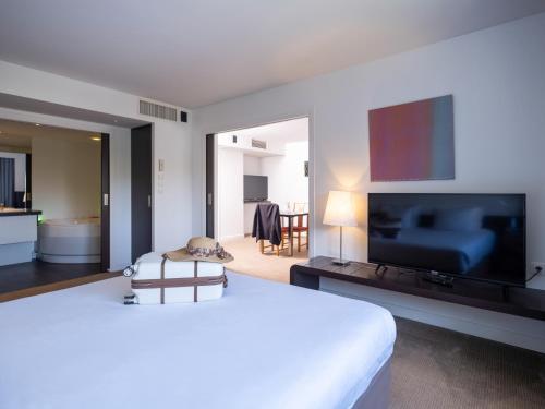 a bedroom with a large bed and a flat screen tv at Novotel Nantes Centre Gare in Nantes