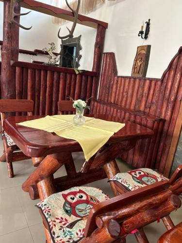 a wooden table and chairs with a yellow table cloth at Pensiunea Miruna in Moieciu de Jos
