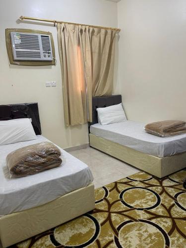 two beds in a room with a fan and a rug at شقق بن طالب in Khamis Mushayt