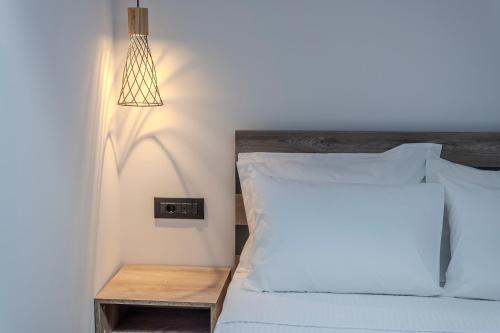 um quarto com uma cama com lençóis brancos e um candeeiro em Dream Luxury Apartments em Stavros
