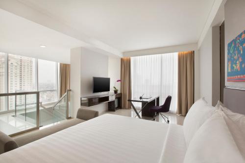 a hotel room with a bed and a desk and a television at Hotel Santika Premiere Hayam Wuruk Jakarta in Jakarta