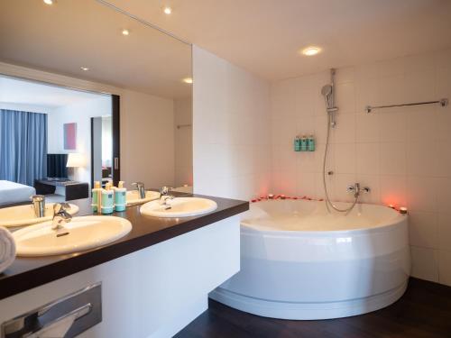 a bathroom with two sinks and a bath tub at Novotel Nantes Centre Gare in Nantes