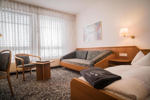 カールスルーエにあるアルファ ホテル スーペリアのベッドとソファ付きのホテルルーム
