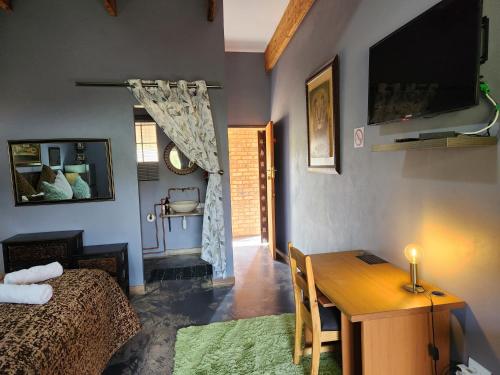 a living room with a bed and a table and a television at Suikerbosrant Sleep and go in Pretoria