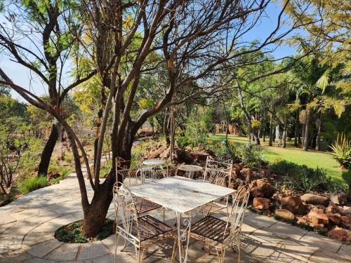 a table and chairs under a tree in a park at Suikerbosrant Sleep and go in Pretoria