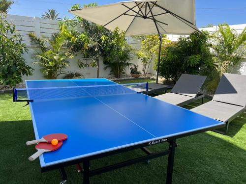 a blue ping pong table in a yard with an umbrella at Lux & Comfy ~ Pool ~ Queen Beds in Rishon LeẔiyyon