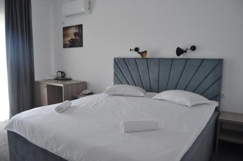 a bedroom with a large white bed with a headboard at Hotel Maya in Horezu