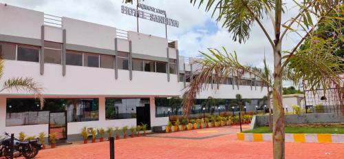 a building with a palm tree in front of it at Hotel Sandhya in Jaypur