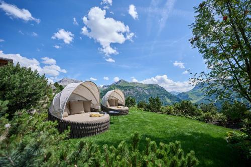 two tents on a grassy hill with mountains in the background at Hotel Mohnenfluh in Lech am Arlberg