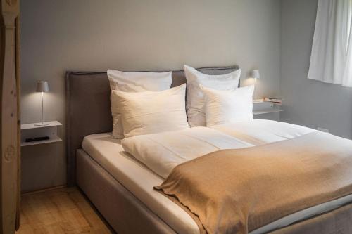 duże łóżko z białą pościelą i poduszkami w obiekcie Ferienwerk w mieście Ofterschwang