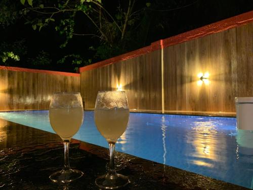 two glasses of wine sitting next to a swimming pool at 3 Bedroom villa with Private Pool in North Goa in Assagao