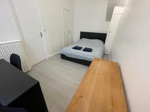 ein kleines Schlafzimmer mit einem Bett und einem Holztisch in der Unterkunft Appartement à 200 mètres de la gare in Rouen