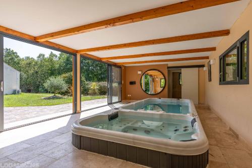una vasca idromassaggio in una stanza con finestre di Jacuzzi - Spa de nage - Parc arboré a Montaigu-de-Quercy