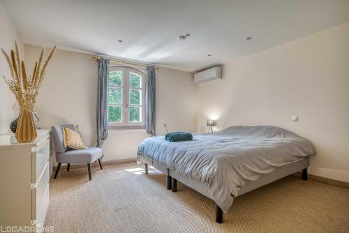 una camera da letto con un letto, una sedia e una finestra di Jacuzzi - Spa de nage - Parc arboré a Montaigu-de-Quercy
