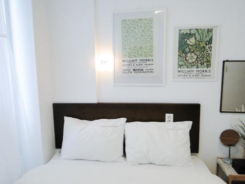 a bedroom with a bed with white pillows and posters at Ekonomy Haeundae Hostel in Busan
