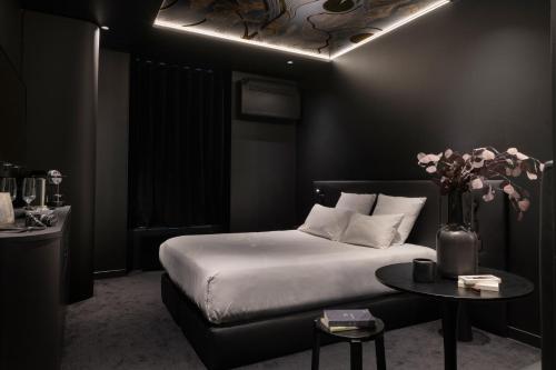 a bedroom with a bed and a table with a vase of flowers at MiHotel Sala in Lyon