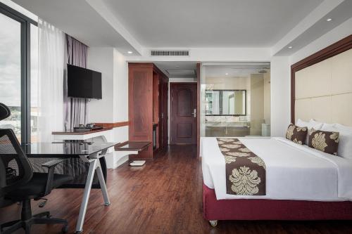 a bedroom with a bed and a desk and a computer at Ohana Phnom Penh Palace Hotel in Phnom Penh