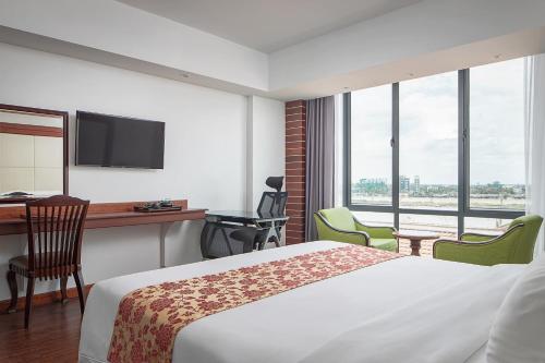 a hotel room with a bed and a desk with chairs at Ohana Phnom Penh Palace Hotel in Phnom Penh