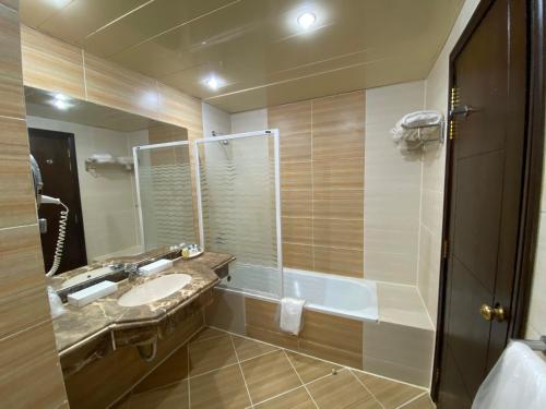 ein Badezimmer mit einem Waschbecken, einer Badewanne und einem Spiegel in der Unterkunft Regency Plaza Aqua Park and Spa Resort in Sharm El Sheikh