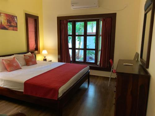ein Schlafzimmer mit Bett, Schreibtisch und Fenster in der Unterkunft 3 Bedroom villa with Private Pool in North Goa in Assagao