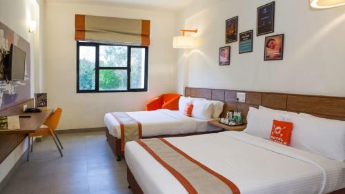 a hotel room with two beds and a desk at Max Hotels Jabalpur in Jabalpur