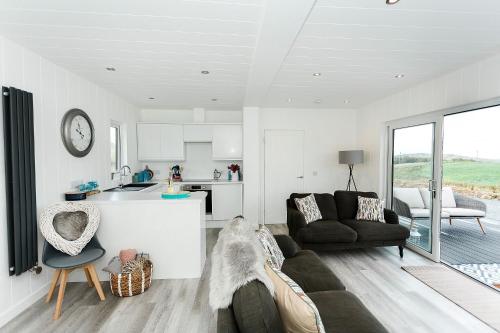 a living room with a couch and a kitchen at Sea Glass Lodge in Gatehouse of Fleet