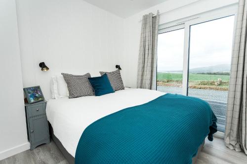 a bedroom with a large bed and a large window at Sea Glass Lodge in Gatehouse of Fleet
