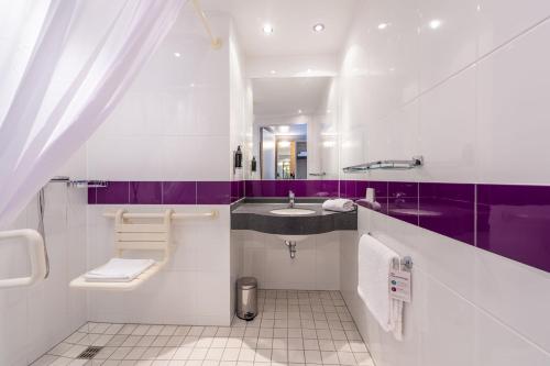 ein lila-weißes Bad mit einem Waschbecken und einem Spiegel in der Unterkunft Premier Inn Stuttgart Airport in Leinfelden-Echterdingen