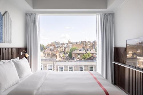 una camera da letto con una grande finestra con vista sulla città di Ruby Zoe Hotel London a Londra