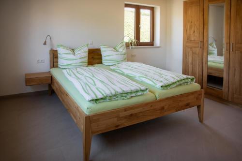 - une chambre avec un lit en bois et des oreillers dans l'établissement Ferienwohnungen Thoma, à Königheim