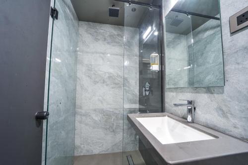 a bathroom with a sink and a glass shower at Hotel Devgiri Inn and Restaurant in Sangli