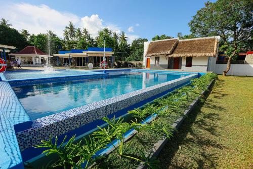 a large swimming pool with a fountain in a yard at B Ternate Resort in Dauin