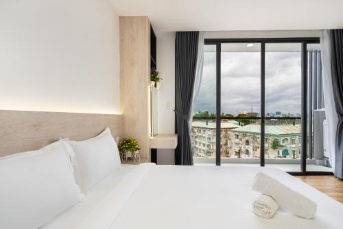 um quarto com uma cama branca e uma grande janela em HAYA BAC HAI Apartments em Ho Chi Minh