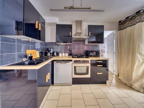 - une cuisine avec des placards bleus, un évier et une cuisinière dans l'établissement LnBnB - Petite maison au cœur de Péronne - Face aux étangs, à Péronne