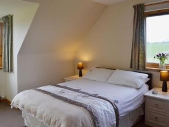 a bedroom with a large bed with a window at Ard Garraidh in Ardersier