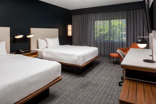 a hotel room with two beds and a desk at Courtyard by Marriott Charlotte Ballantyne in Charlotte