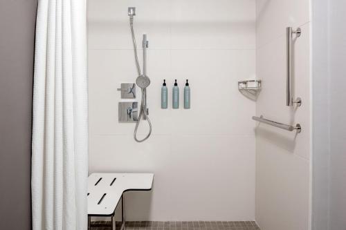 a white bathroom with a shower and a bench at Courtyard by Marriott Charlotte Ballantyne in Charlotte