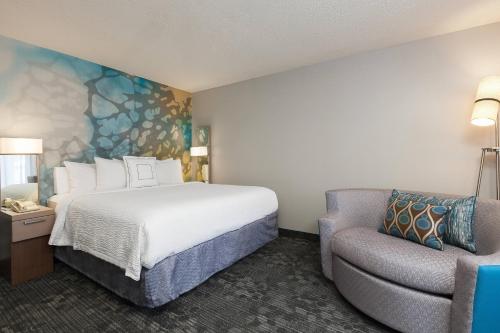 a hotel room with a bed and a chair at Courtyard Dallas Mesquite in Mesquite