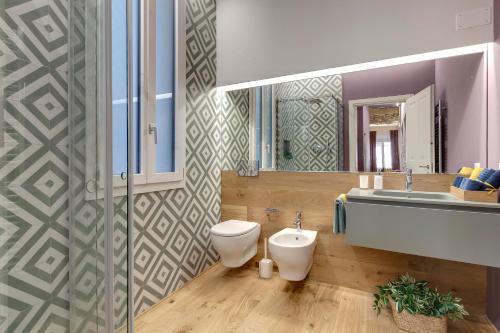 uma casa de banho com um WC, um lavatório e um espelho. em Mamo Florence - Aperol & Spritz Apartments em Florença