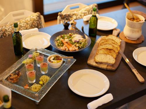 a table with plates of food and bottles of wine at GLAMP ELEMENT(グランエレメント） in Maibara