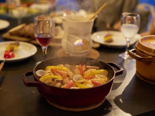 a bowl of food on a table with glasses of wine at GLAMP ELEMENT(グランエレメント） in Maibara