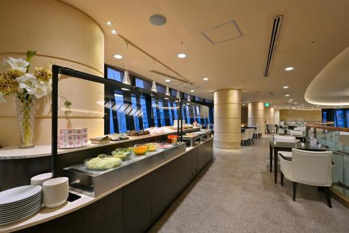 un restaurante con una línea de buffet con platos y mesas en Wakayama Urban Hotel, en Wakayama