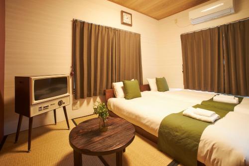 Habitación de hotel con 2 camas y TV en Kagurazaka Retro BAR & HOTEL, en Tokio
