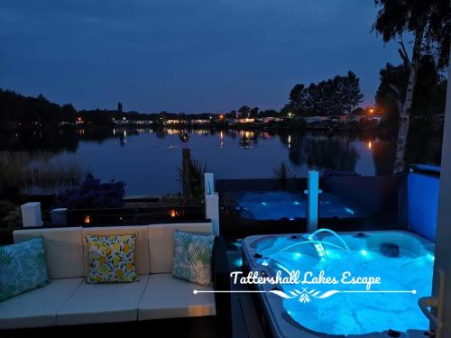 a jacuzzi tub sitting on a balcony overlooking a lake at Meridian Tattershall Lakes Escape - Lakeside lodge caravan with a fishing peg LUXURY HOT TUB in Tattershall
