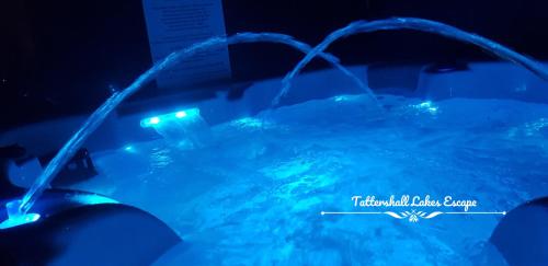 a swimming pool with blue lights in a dark room at Meridian Tattershall Lakes Escape - Lakeside lodge caravan with a fishing peg LUXURY HOT TUB in Tattershall
